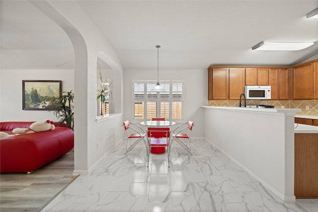 dining area featuring arched walkways, marble finish floor, and baseboards