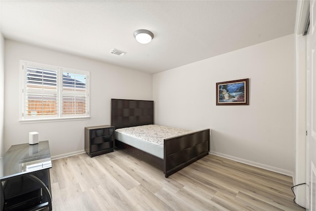 bedroom with light wood-style flooring, visible vents, and baseboards