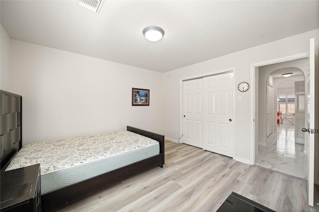 bedroom featuring arched walkways, a closet, visible vents, and baseboards