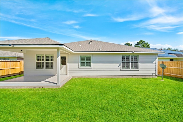 back of house featuring a fenced backyard, roof with shingles, a lawn, and a patio