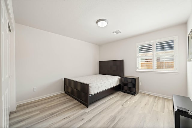 bedroom featuring visible vents, light wood-style flooring, and baseboards