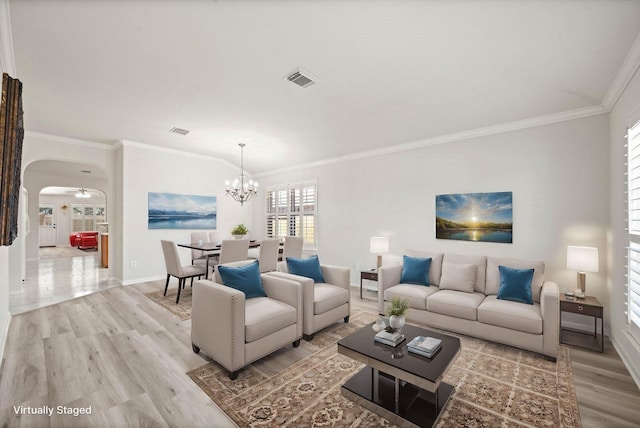 living room with arched walkways, visible vents, light wood-style floors, ornamental molding, and baseboards