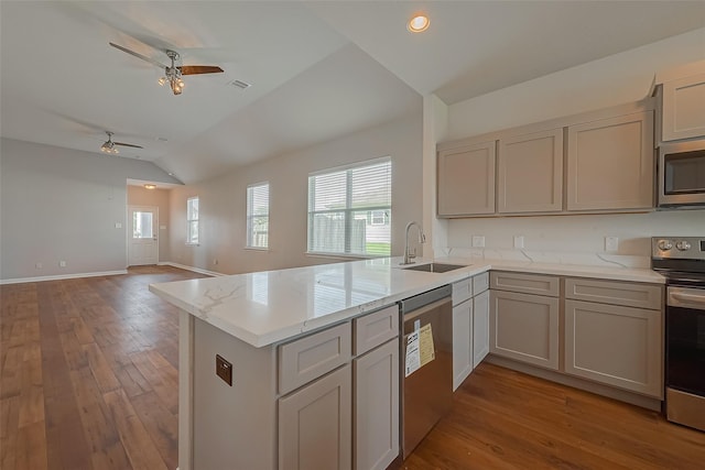 kitchen with appliances with stainless steel finishes, open floor plan, a sink, and a peninsula