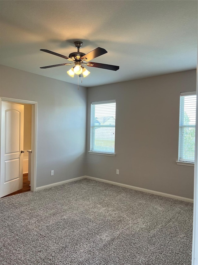 empty room with carpet, a ceiling fan, and baseboards