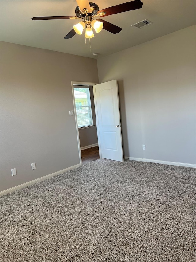 carpeted empty room featuring ceiling fan, visible vents, and baseboards