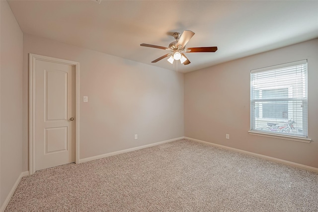 carpeted spare room featuring ceiling fan and baseboards