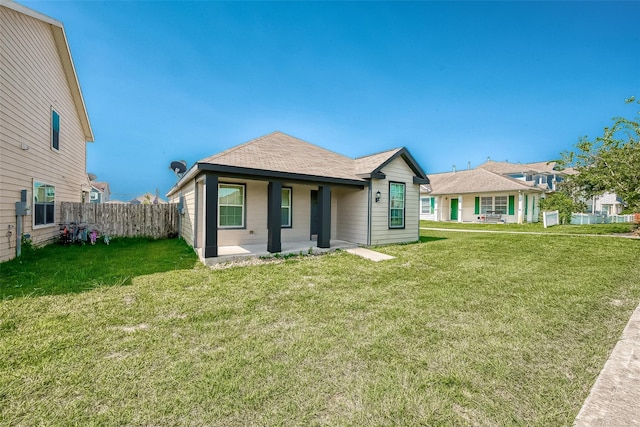 bungalow featuring a patio, a shingled roof, a front yard, and fence