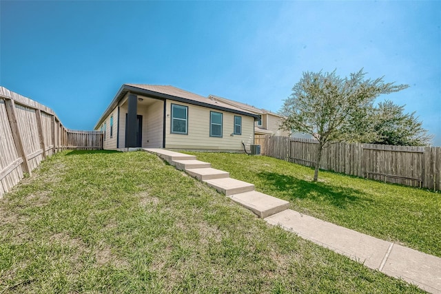 back of property with a yard, a fenced backyard, and central air condition unit