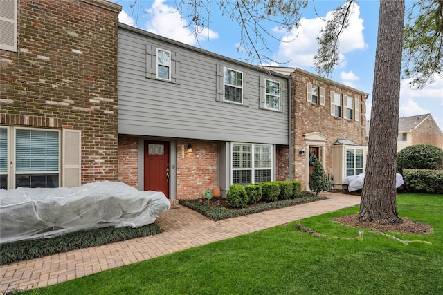 multi unit property featuring a front yard and brick siding