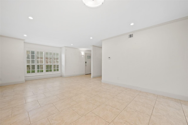 empty room featuring baseboards, visible vents, and ornamental molding