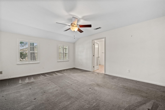 empty room with light colored carpet, a ceiling fan, baseboards, vaulted ceiling, and visible vents