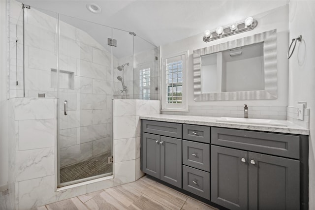 bathroom with lofted ceiling, a stall shower, and vanity