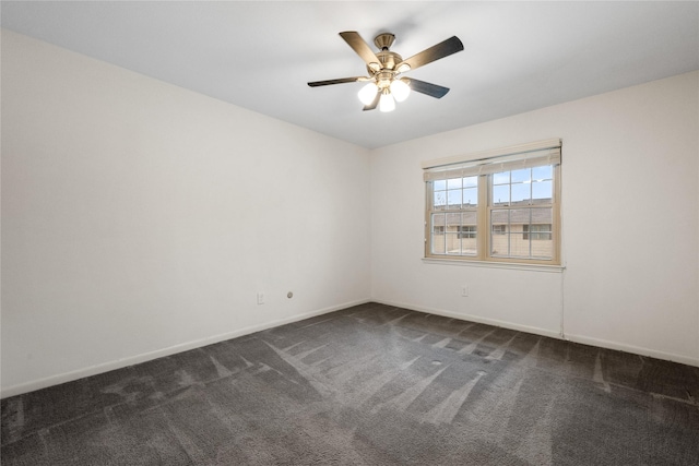 empty room featuring dark carpet, a ceiling fan, and baseboards