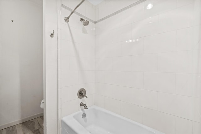 bathroom with wood finished floors, shower / tub combination, toilet, and baseboards