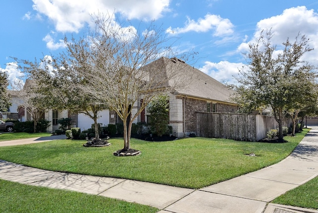 view of side of property with a garage, brick siding, fence, driveway, and a lawn