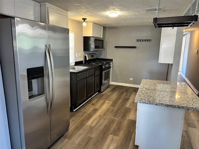 kitchen featuring visible vents, appliances with stainless steel finishes, dark wood-type flooring, light stone countertops, and a textured ceiling