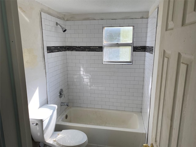 bathroom featuring toilet, shower / tub combination, and a textured ceiling