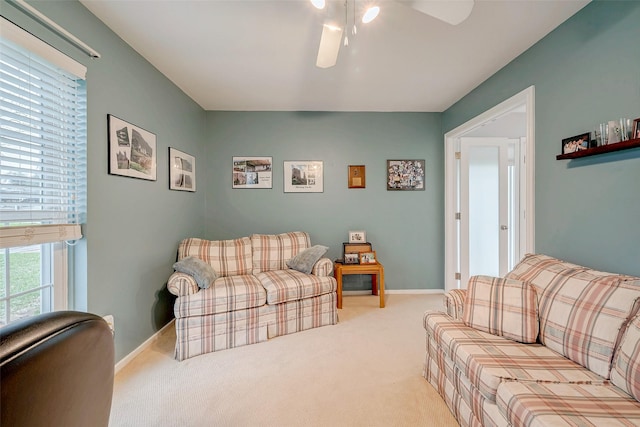 living area featuring light carpet, ceiling fan, baseboards, and a wealth of natural light