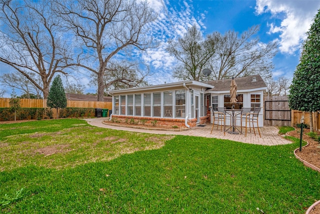 rear view of property with a fenced backyard, brick siding, a sunroom, a lawn, and a patio area