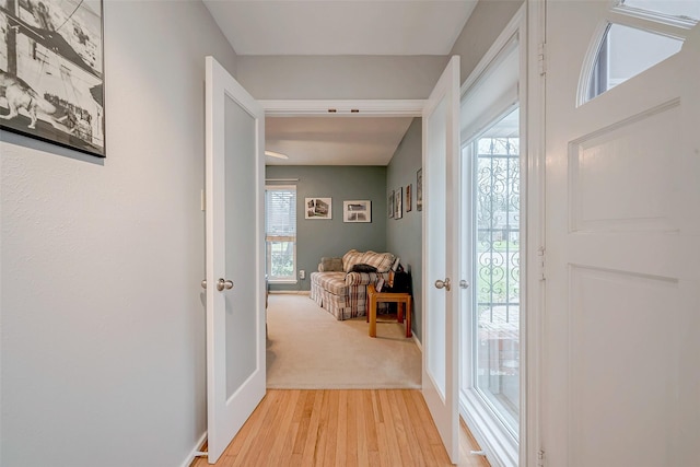 doorway to outside with light wood finished floors, baseboards, and a wealth of natural light