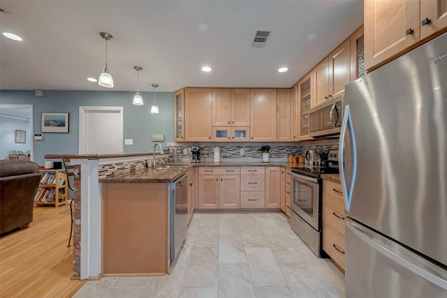 kitchen featuring hanging light fixtures, light brown cabinetry, appliances with stainless steel finishes, dark stone countertops, and a peninsula