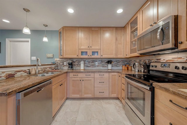 kitchen featuring light stone counters, light brown cabinets, stainless steel appliances, a sink, and hanging light fixtures