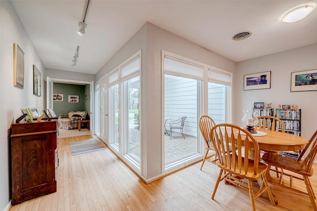 dining space with visible vents, light wood-style flooring, and track lighting