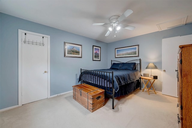 bedroom with light carpet, attic access, baseboards, and a ceiling fan