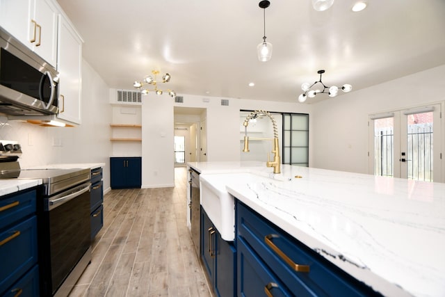 kitchen featuring blue cabinetry, appliances with stainless steel finishes, white cabinets, and a notable chandelier