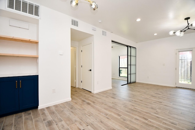 unfurnished room with light wood-type flooring, visible vents, and a healthy amount of sunlight