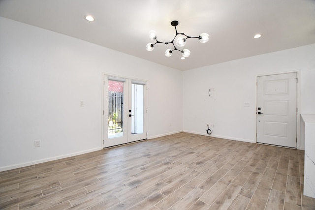 unfurnished room with a chandelier, light wood-style flooring, recessed lighting, baseboards, and french doors