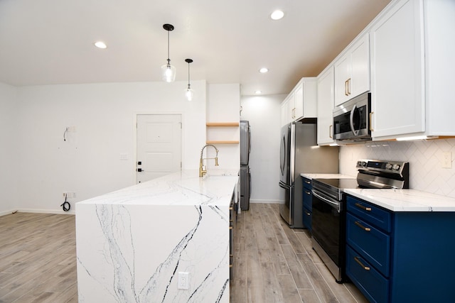 kitchen with stainless steel appliances, white cabinets, blue cabinetry, decorative backsplash, and decorative light fixtures