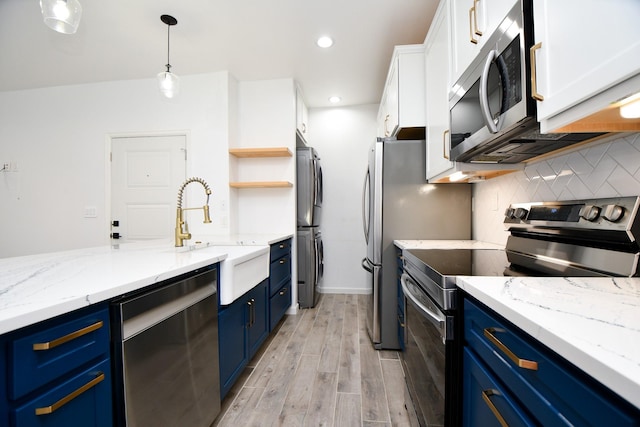 kitchen with tasteful backsplash, appliances with stainless steel finishes, blue cabinetry, white cabinetry, and a sink