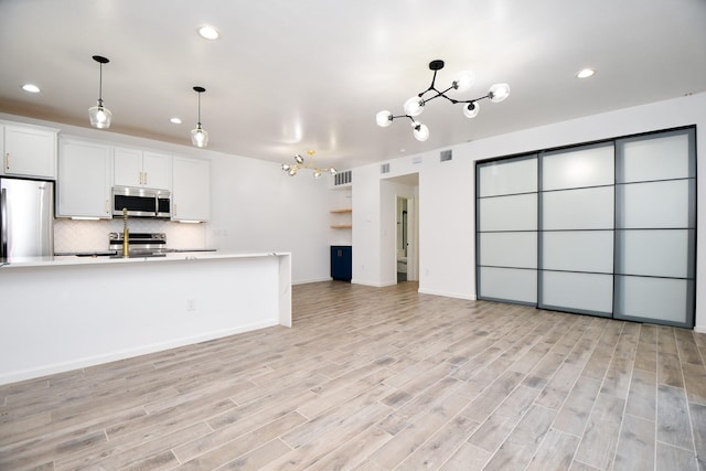 kitchen with light wood finished floors, stainless steel appliances, tasteful backsplash, light countertops, and white cabinetry