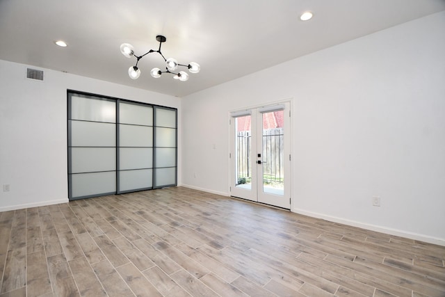 unfurnished room featuring a chandelier, baseboards, visible vents, and light wood-style floors