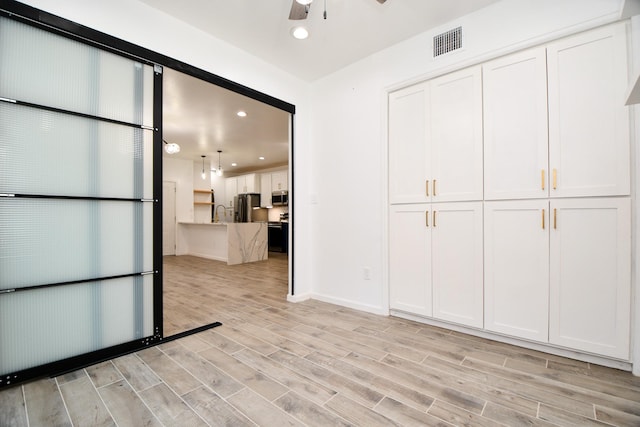 hall with light wood-style floors, baseboards, visible vents, and recessed lighting