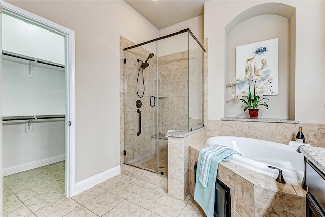 bathroom with a walk in closet, tile patterned flooring, a garden tub, and a shower stall