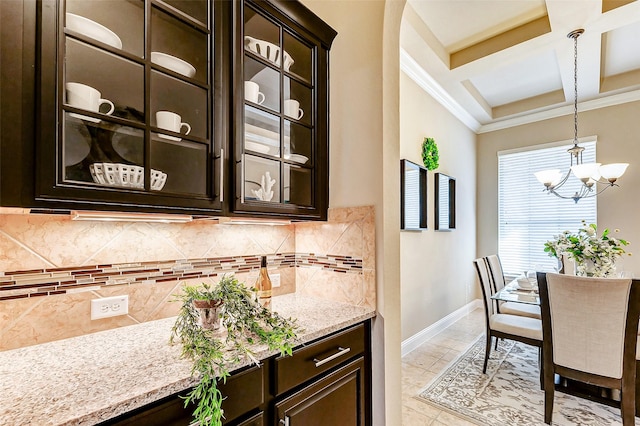 kitchen featuring pendant lighting, backsplash, glass insert cabinets, dark brown cabinetry, and coffered ceiling