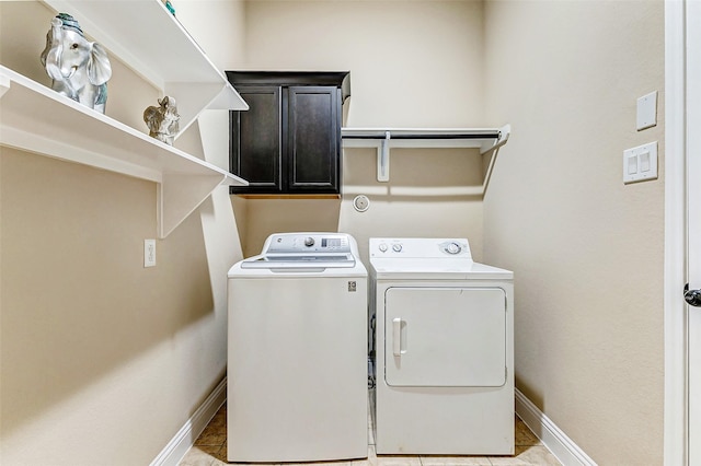 washroom featuring washer and clothes dryer, cabinet space, and baseboards