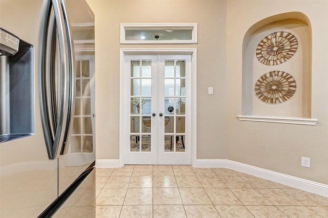 doorway with baseboards, light tile patterned flooring, and french doors