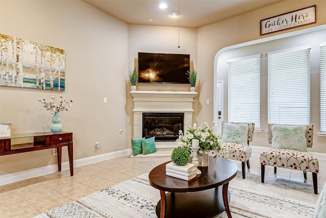 living room with tile patterned flooring, baseboards, and a glass covered fireplace