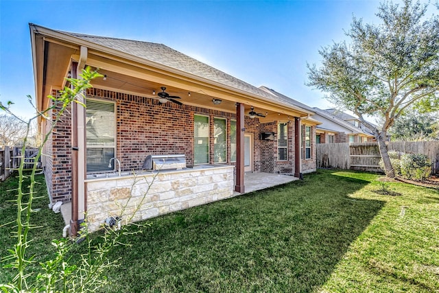 rear view of house with a ceiling fan, brick siding, fence, and a patio