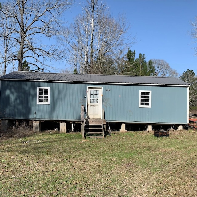 view of front of home featuring entry steps, metal roof, and a front lawn