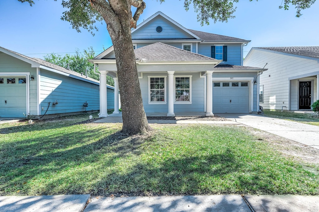 view of front of house featuring a shingled roof, a front yard, concrete driveway, and an attached garage