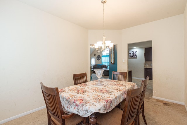 dining area featuring a chandelier, light colored carpet, and baseboards