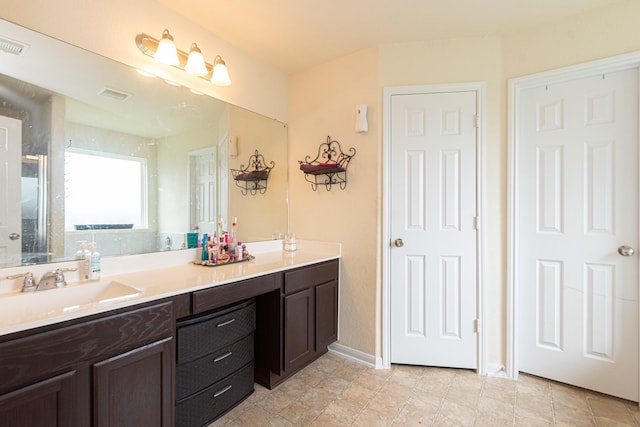 full bathroom with double vanity, baseboards, visible vents, and a sink