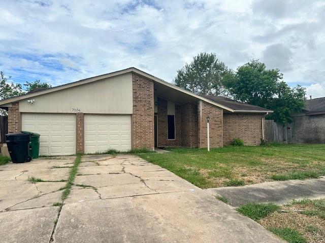 view of front of property featuring an attached garage, brick siding, concrete driveway, and a front yard