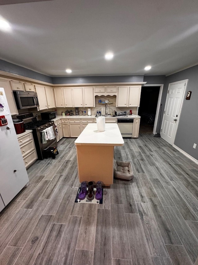 kitchen featuring wood finished floors, light countertops, appliances with stainless steel finishes, and a kitchen island