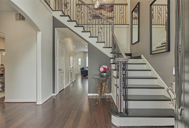 entryway featuring arched walkways, a high ceiling, wood finished floors, and baseboards