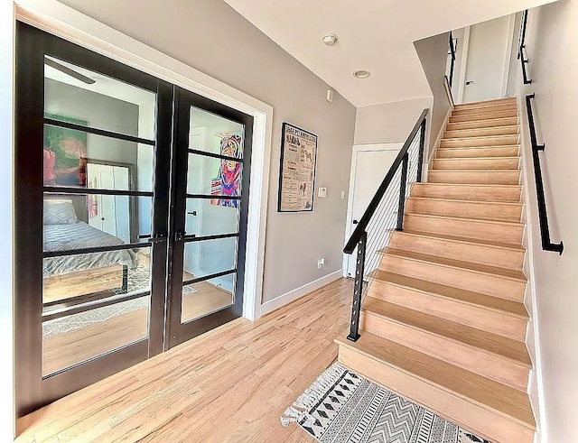 stairs with french doors, wood finished floors, and baseboards